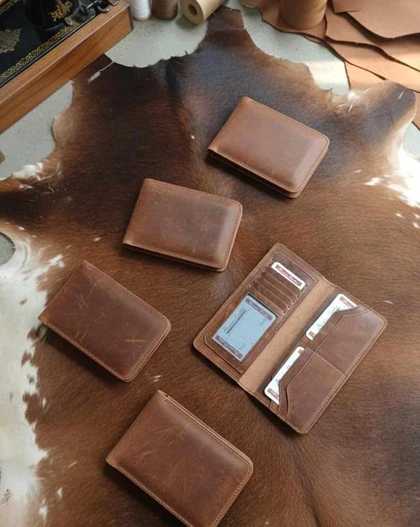 Collection of brown leather wallets on a cowhide surface